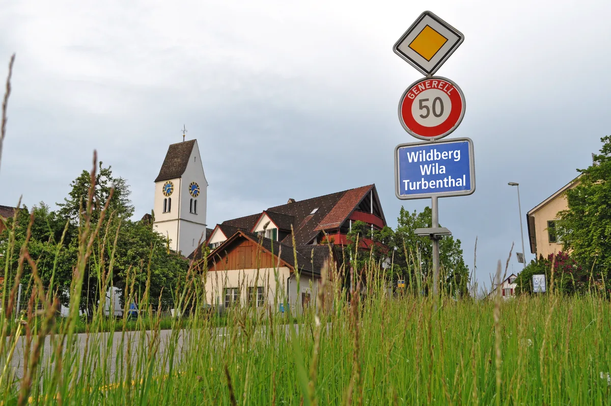 Ortstafel und eine Kirche im Hintergrund.